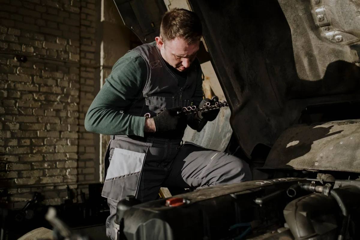 A mechanic holding a replacement part beside an open engine